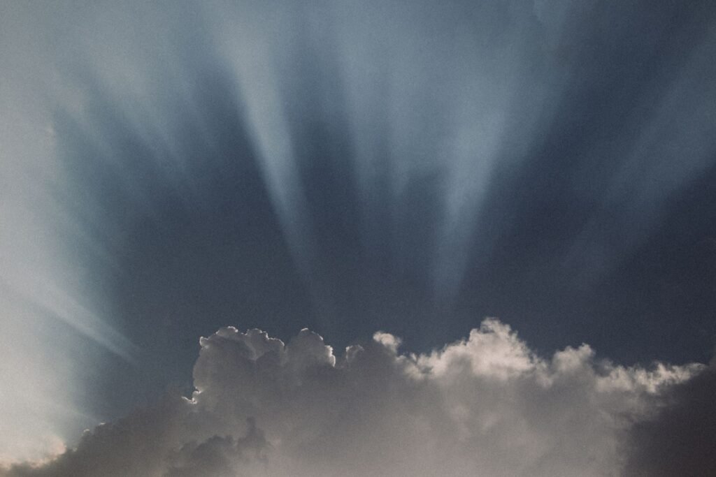 Dramatic sunbeams penetrate through clouds, creating a captivating sky scene.