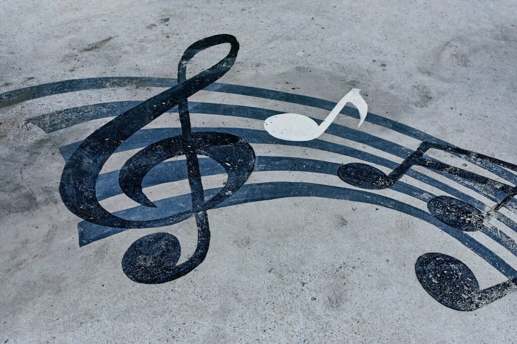 A black treble clef and musical notes painted on a grey concrete surface