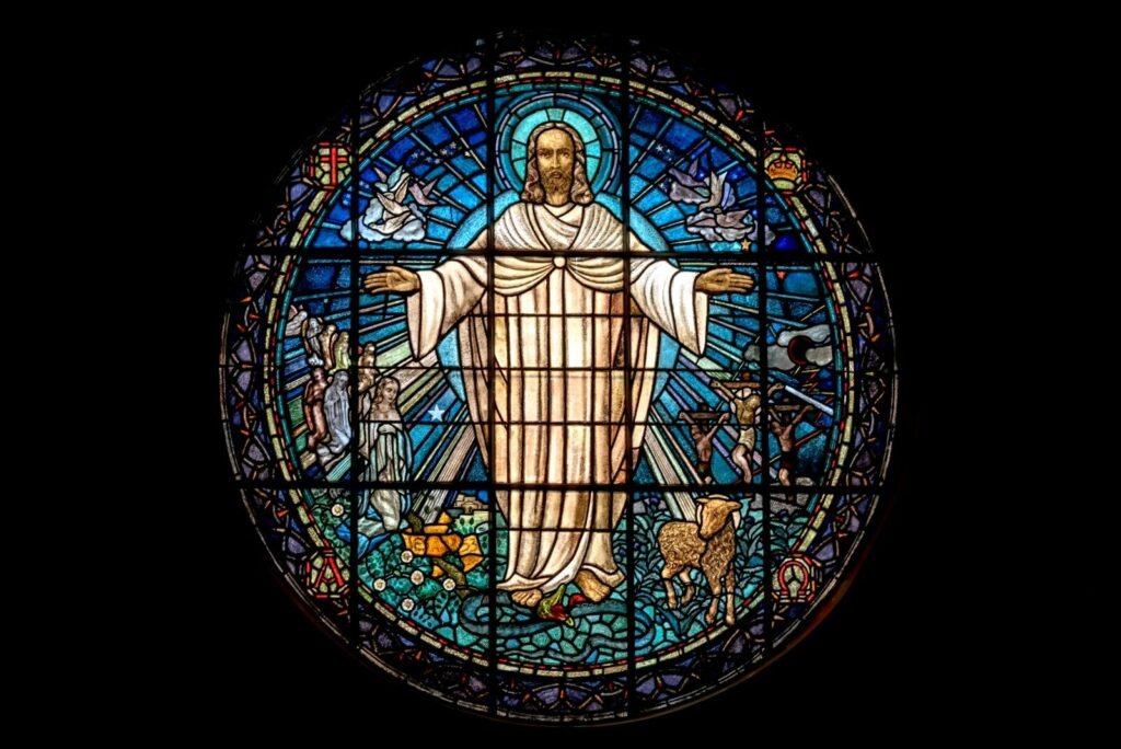 A circular stained glass window depicting a central figure with arms outstretched