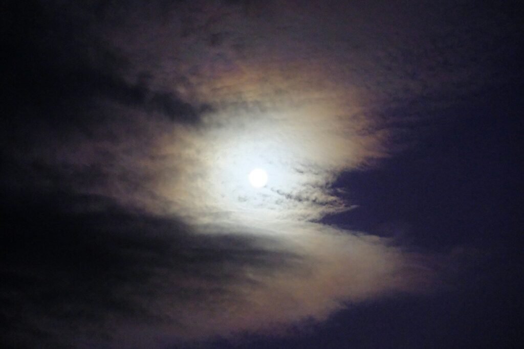 A full moon in a cloudy sky with clouds
